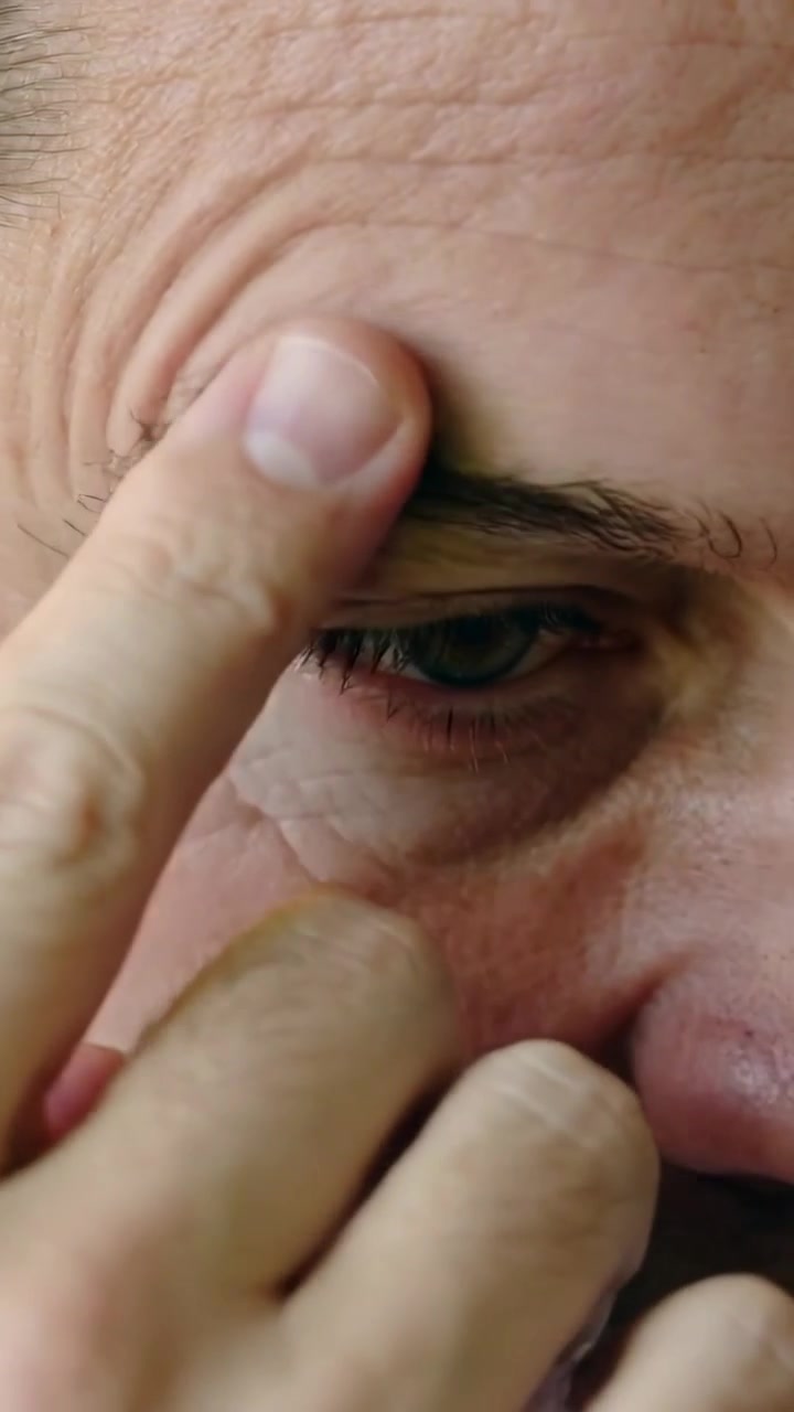 Video verticale: Uomo che preme la parte interna del sopracciglio con il dito indice, massaggiandosi la tempia per alleviare la tensione.