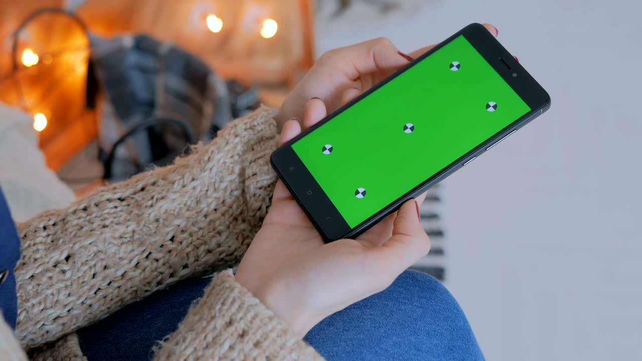 mujer mirando un teléfono inteligente con pantalla verde