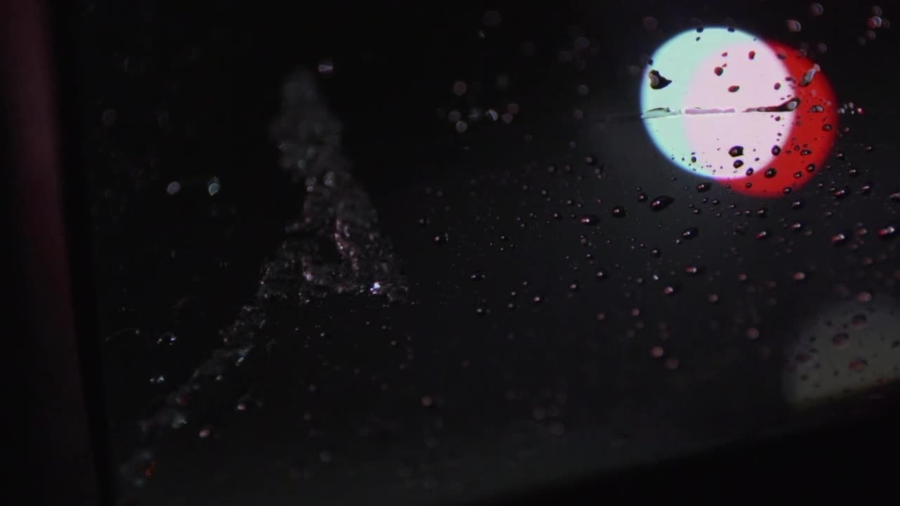 Snow melting onto windshield at night with defocused traffic lights