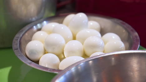 cook places freshly peeled hard boiled eggs into full bowl, slow motion hd