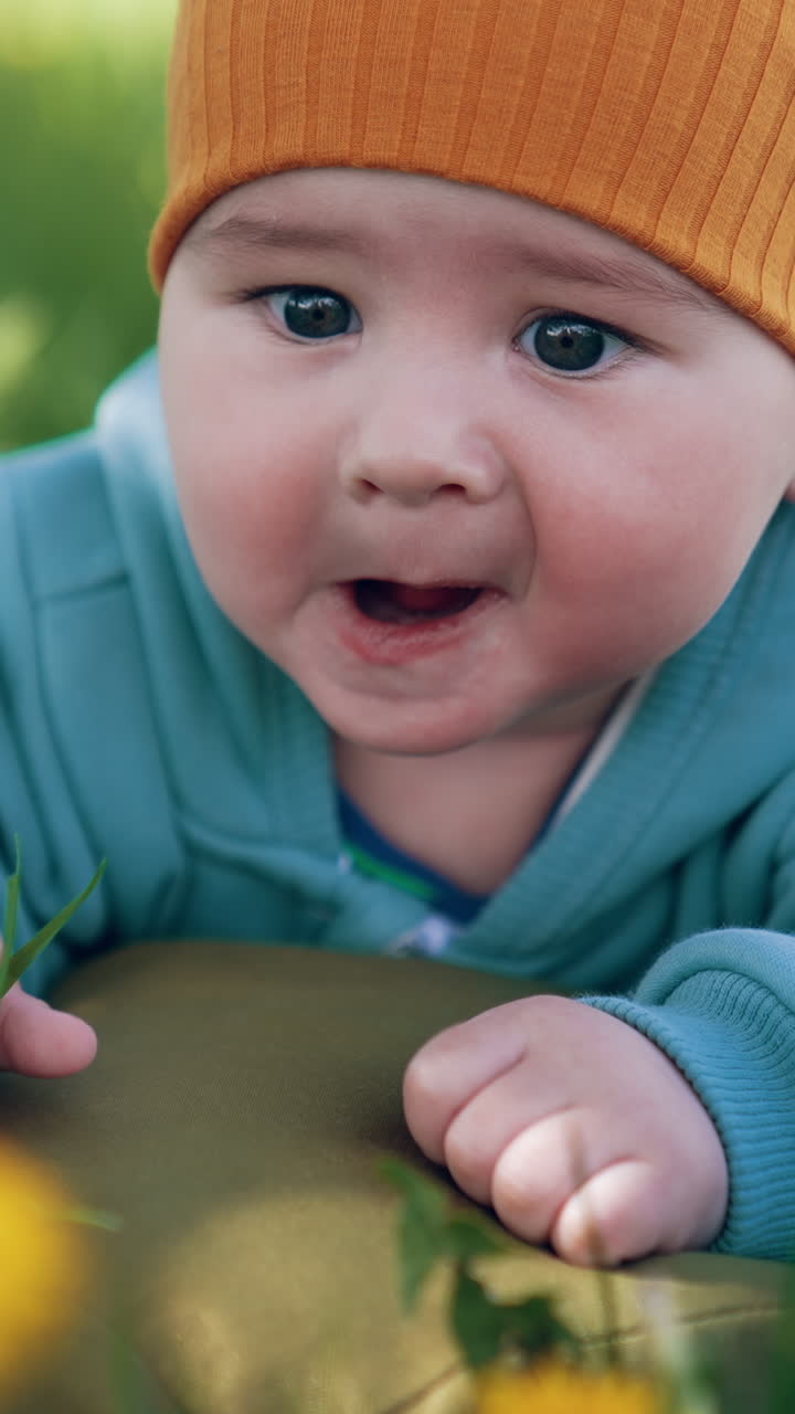 Baby boy in orange hat and blue jacket in a park
