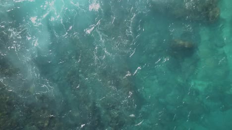 Aerial-view-of-the-crystal-blue-water-of-broken-bay-in-Nusa-Penida,-Indonesia,-camera-spinning