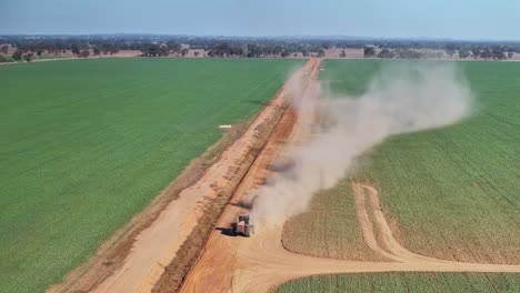 Riesige-Staubwolken-Steigen-Von-Einem-Traktor-Auf,-Der-Einen-Kleinen-Straßenhobel-Auf-Einem-Feldweg-Zieht