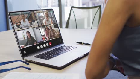 Mujer-Afroamericana-Usando-Una-Computadora-Portátil-Para-Videollamadas,-Con-Diversos-Colegas-De-Negocios-En-La-Pantalla