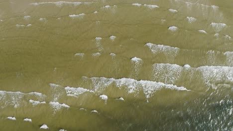 tropical beach aerial view, top view of waves break on tropical white sand beach. sea waves seamless loop on the beautiful sand beach.