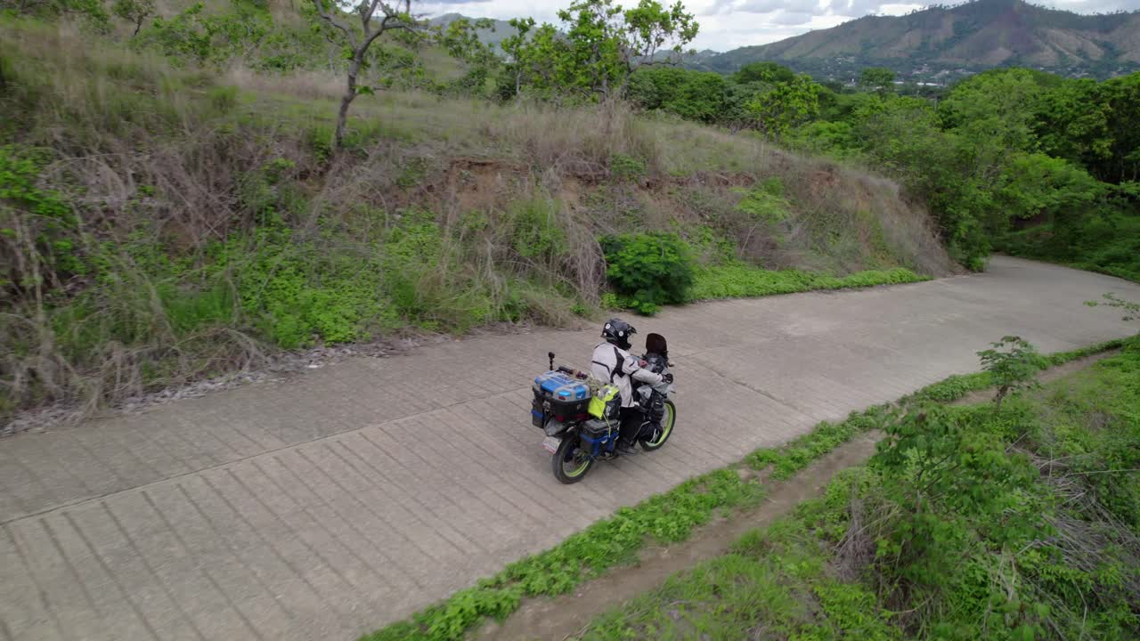 Drone follows motorbike down lush road from San Juan Morros view