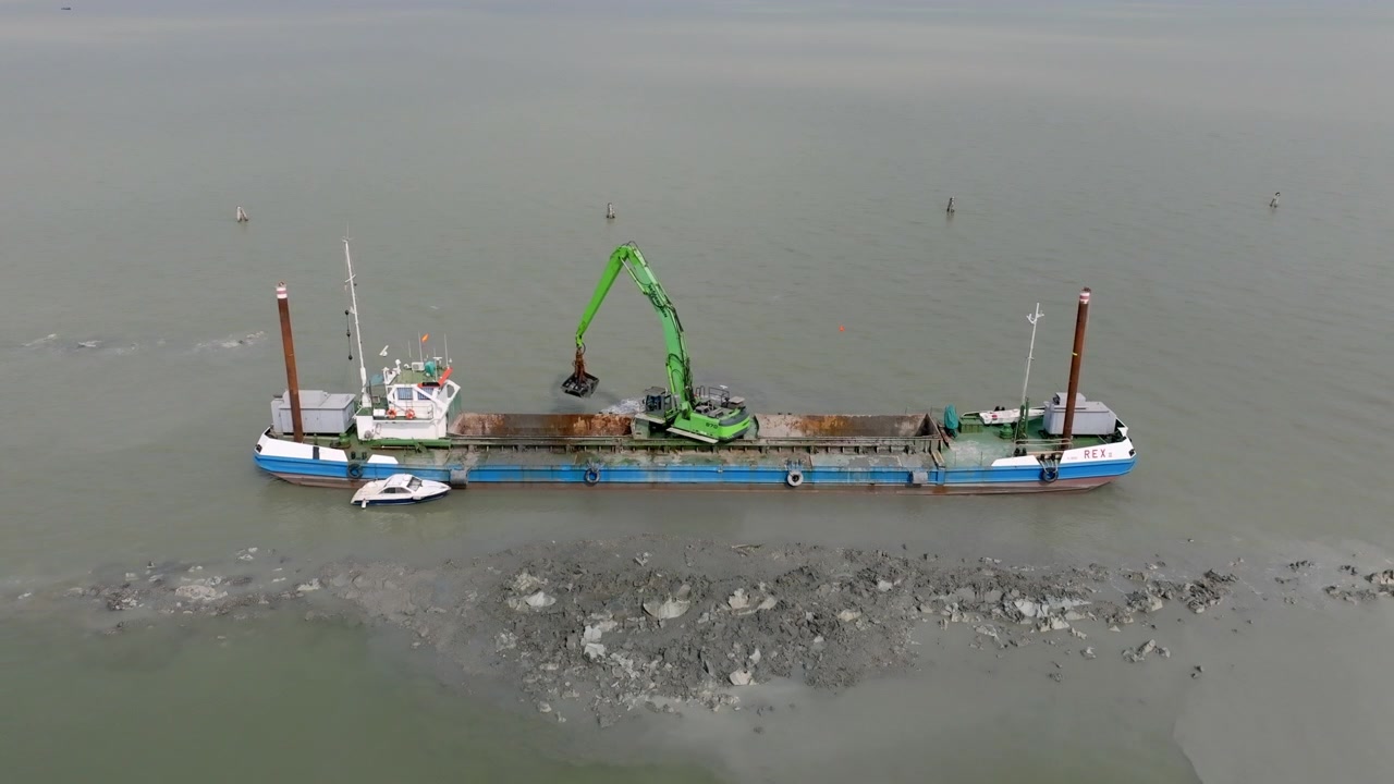 Nave ancorata nella Laguna di Venezia con una draga che rimuove fango