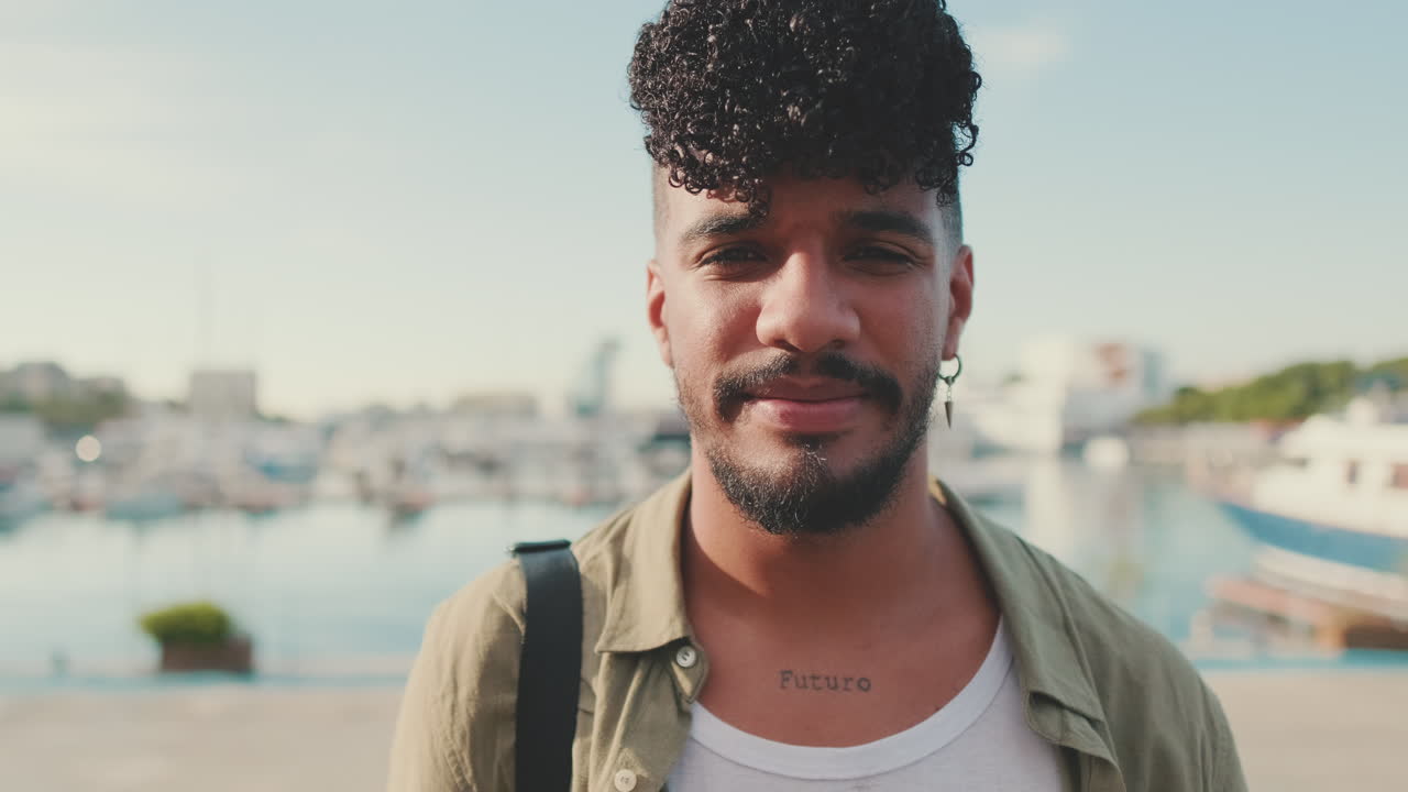 Portrait of a man with curly hair and a tattoo in a marina