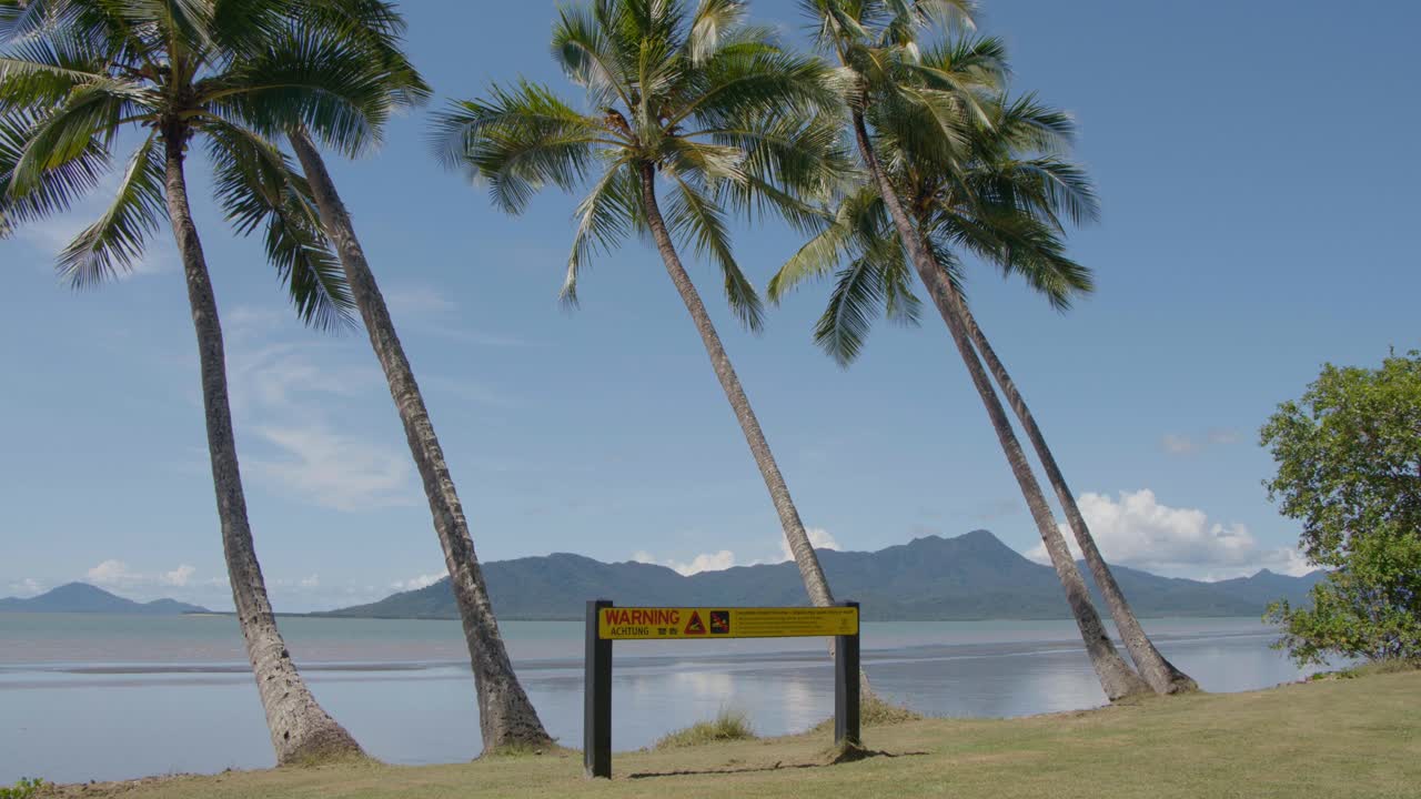 느린 움직임의 바람이 바 ⁇ 가와 섬의 배경과 함께  ⁇ 에 경고 표지판 위에  ⁇ 나무를 불어넣고 있습니다.