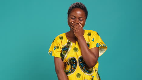 Cute-female-model-giggling-against-blue-background-in-studio