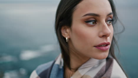 retrato de una hermosa mujer joven de pie frente a un paisaje marino gris y sombrío sola.