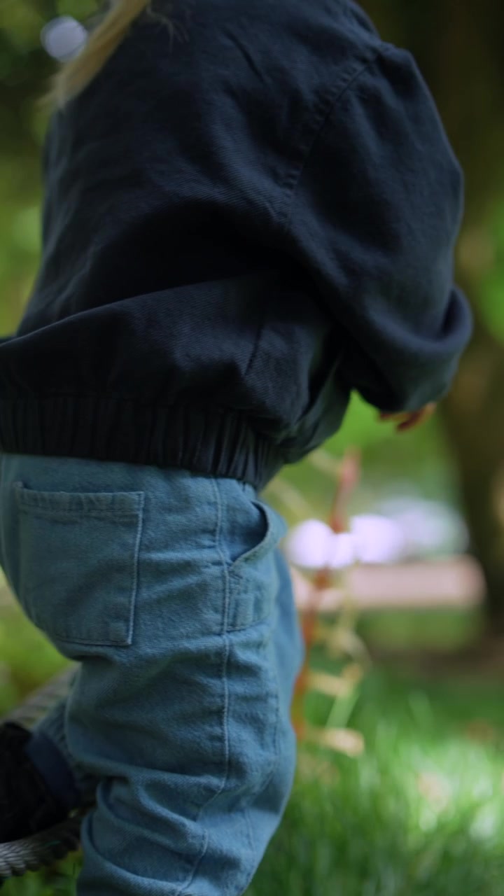 Bambino piccolo che esplora una corda in un parco verde
