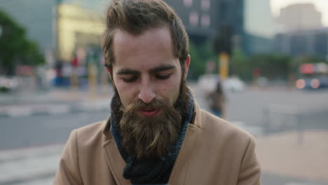 Primer-Plano-Retrato-De-Un-Atractivo-Y-Elegante-Joven-Hipster-Barbudo-Enviando-Mensajes-De-Texto-Navegando-Usando-Una-Aplicación-De-Mensajería-Para-Teléfonos-Inteligentes-En-Las-Calles-De-La-Ciudad