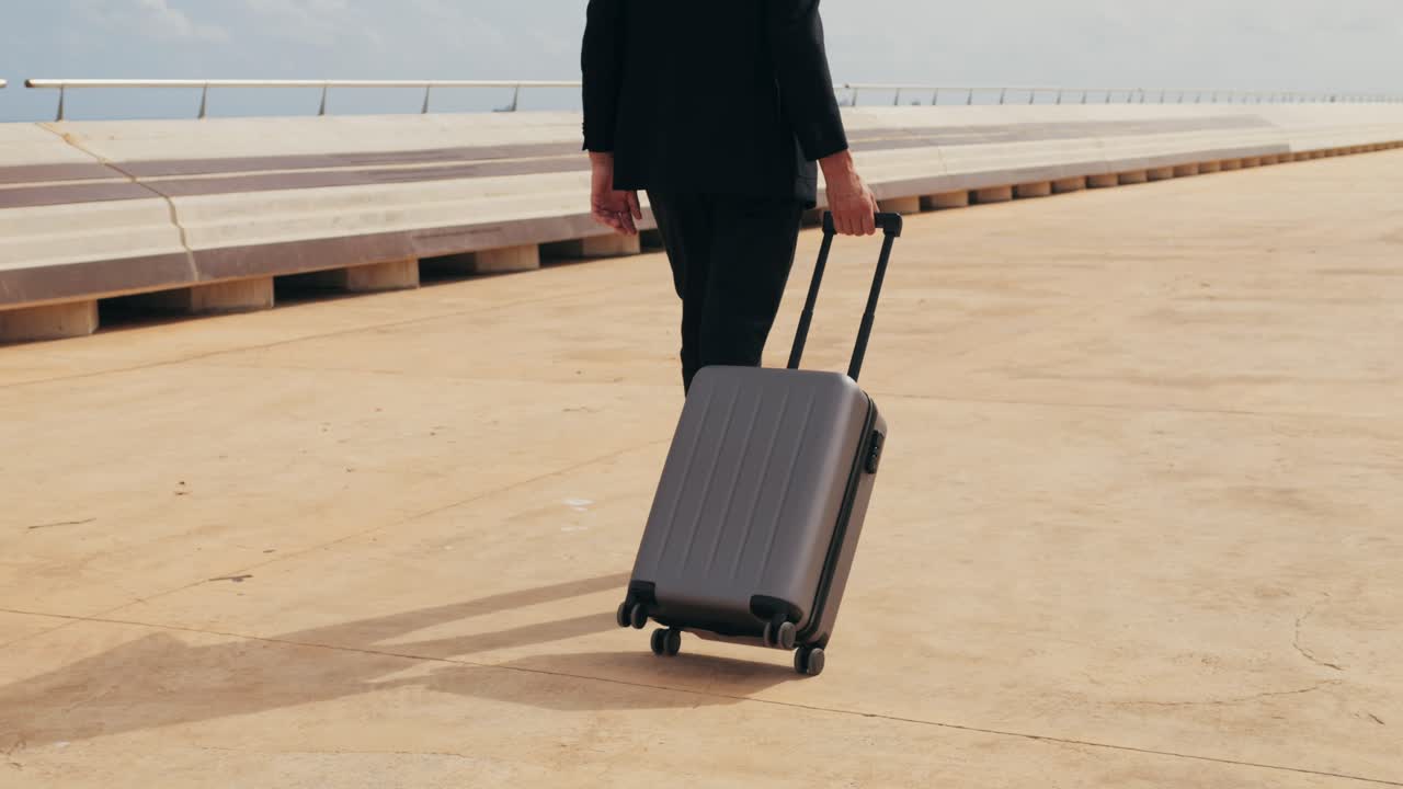 Toerist met kofferbagage in Spanje, een reiziger met bagage en een kostuumjas op een zakenstraat op weg naar een hotel, kantoor, luchthaventerminal, genietend van de levendige sfeer