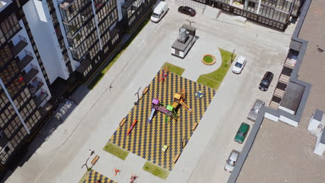 children's playground surrounded by tall buildings. modern district in the city with high-raised apartments and a playground inside. aerial view.