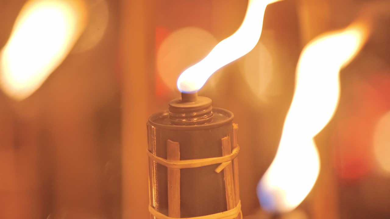 Burning torch close up with twisting flame and smoke in windy Latvian evening