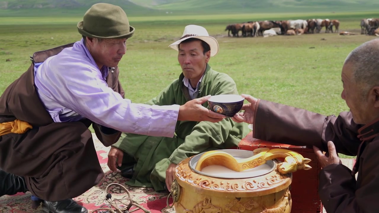 Mongolští nomádi sdílející tradiční čaj a občerstvení na stepi.