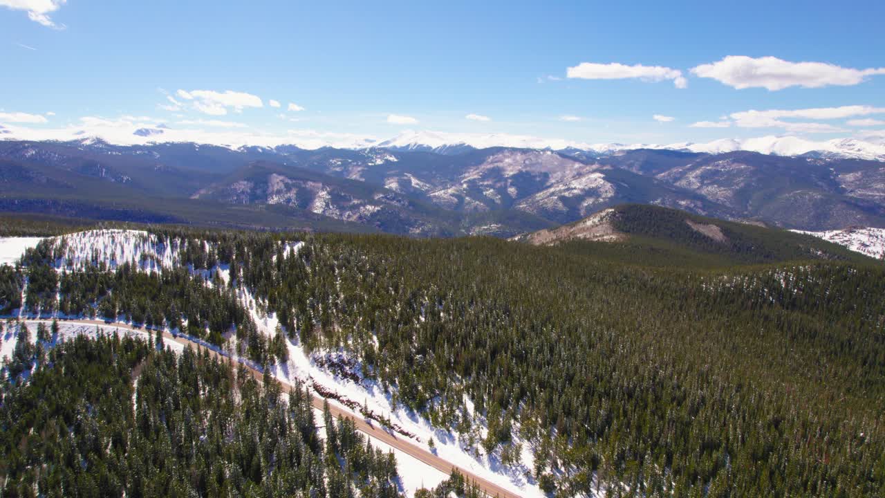 dron aéreo que establece un disparo volando sobre las colinas nevadas del bosque alpino con la cordillera de las montañas rocosas en el fondo cerca del monte evans, colorado, ee.uu.