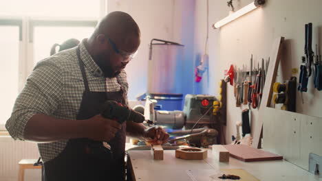 craftsperson sinks screws into wood block with electric tool
