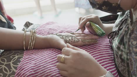 henna artist applying mehndi on bride's palm and