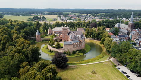 kasteel-huis-bergh:-aerial-view-in-orbit-of-the-fantastic-castle-and-appreciating-the-moat,-the-nearby-trees,-the-towers-and-the-nearby-church