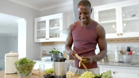 feliz hombre afroamericano preparando un batido saludable en la cocina en casa, en cámara lenta