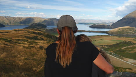 two women embracing while enjoying a stunning lake and mountain view