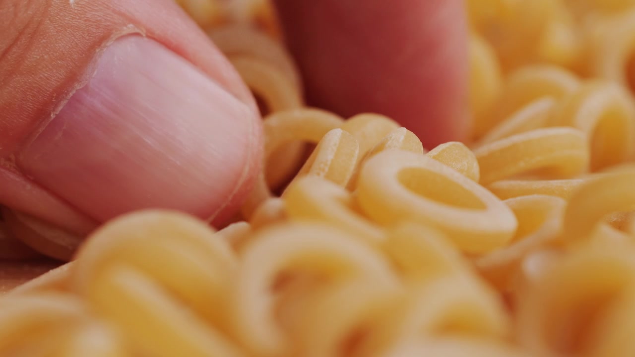 Pasta integrale biologica, maccheroni di semola di grano duro, penne rigate crude in una ciotola di legno. Filmato 4k di alta qualità