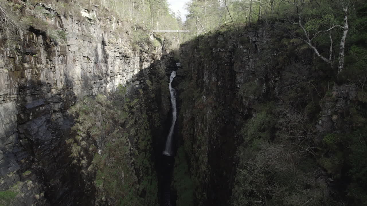 Droneopptak som flyr vekk fra stor foss inne i den smale og steinete Corrieshalloch-juvet i det skotske høylandet