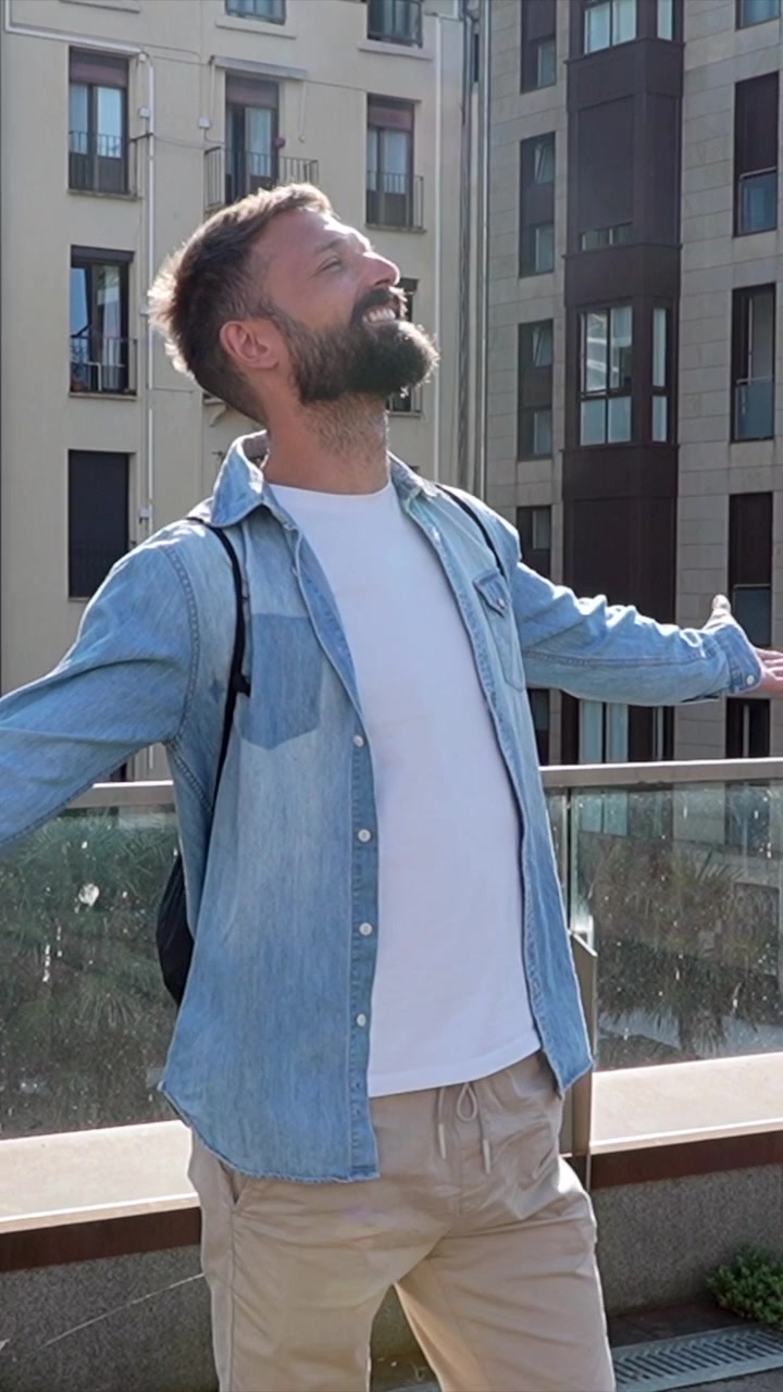 Uomo felice in piedi su una terrazza urbana con le braccia distese