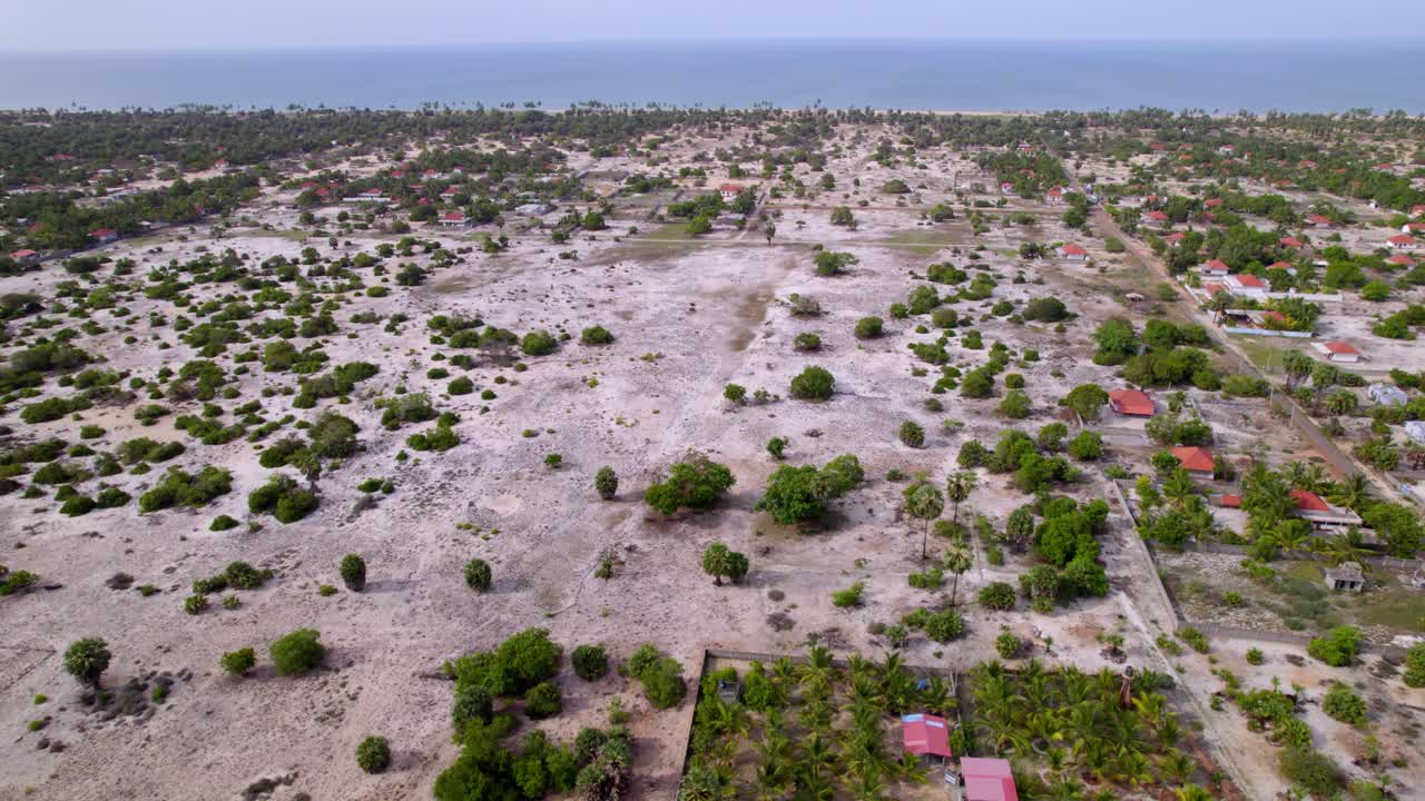 Toma aérea de establecimiento de terreno arenoso y casas dispersas en la aldea de Uduthurai, con fondo de travelling