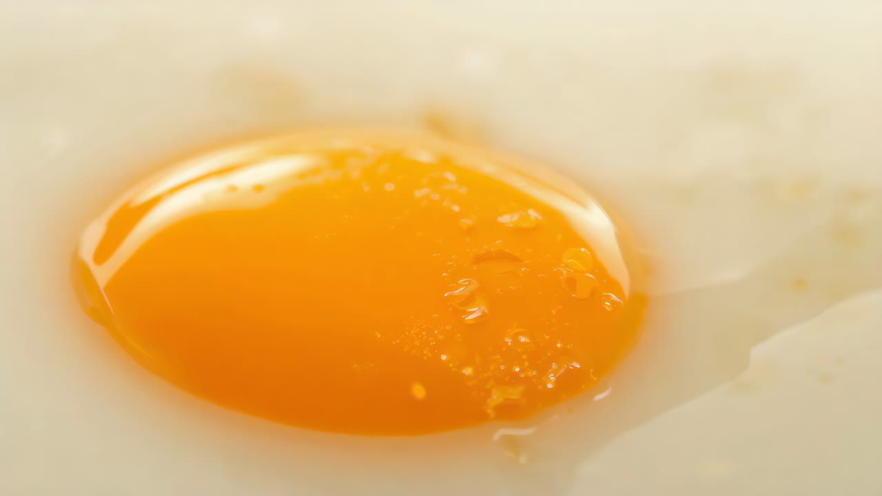 Recording fried egg yolk shifting droplets while camera focusing on frying pan, revealing bubbles