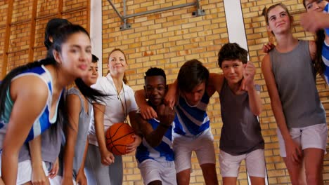 excited sports teacher and school students cheering in basketball court