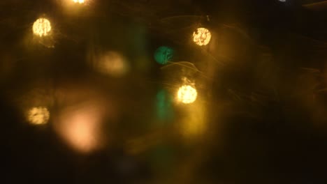 night dirty window with blinking golden and green bokeh lights background