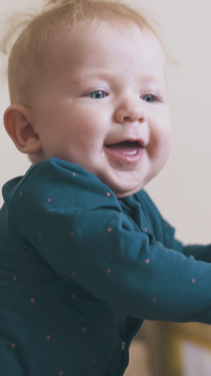 adorable little baby in dark green clothes plays with elder sister at yellow playpen in modern children room