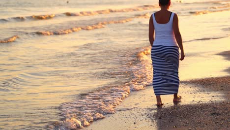 lonely woman walking on beach. back portrait girl walking on sea beach in stylish wear