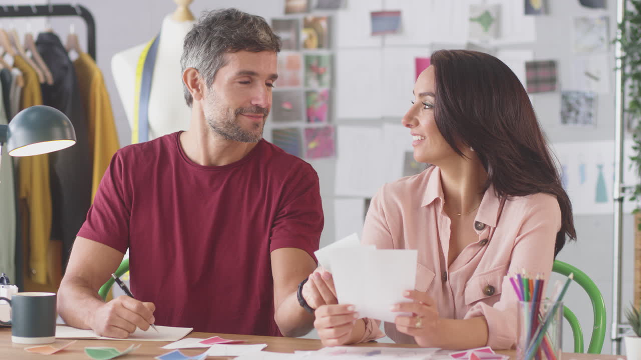 diseñadores de moda masculinos y femeninos en el escritorio en el estudio discutiendo muestras de colores
