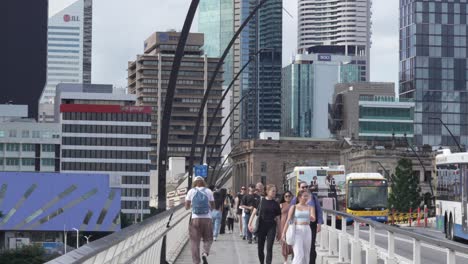 group of people walking in brisbane australia on foot bridge, city buildings view