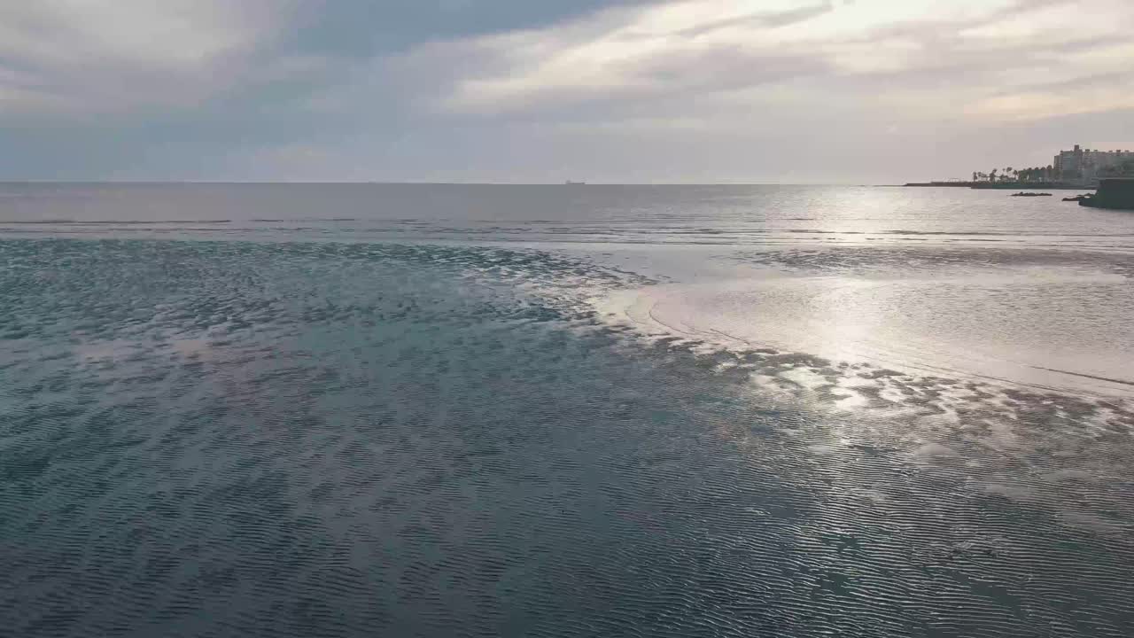 Sunlight reflects on calm sea water surface, creating gentle ripples and a tranquil atmosphere