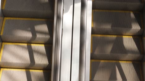 moving up the escalator with glass sides and metal steps. escalator moving in shopping mall. close up view.