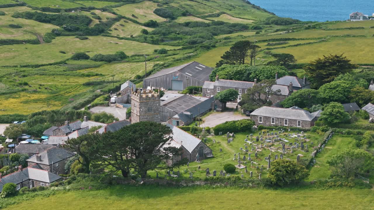 Aerial flyover of Zennor coastal hills and countryside leading to rugged cliff edges, establishing of village church and graveyard