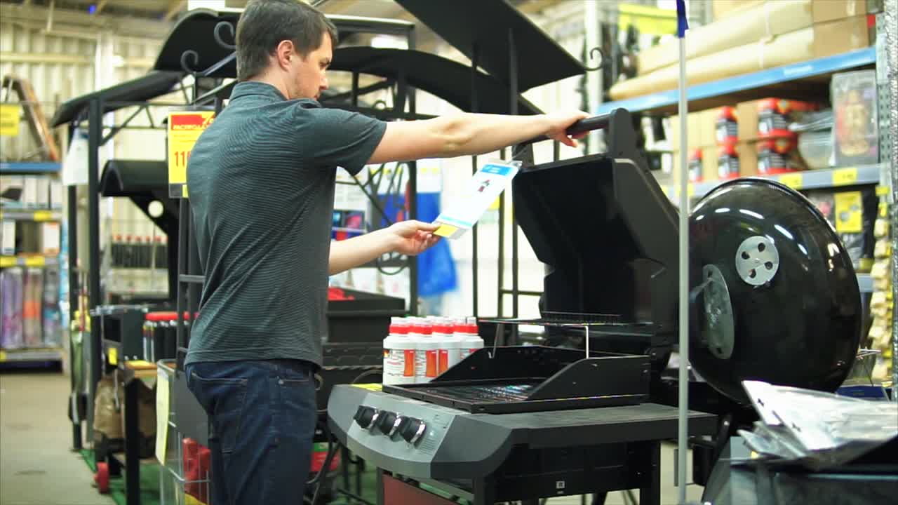 가정용 장비 가게 에서 가스 그릴 을 보고 있는 사람