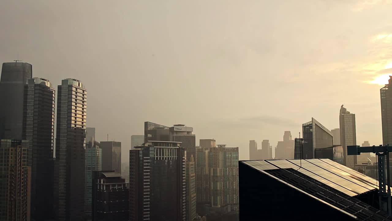 Paisaje urbano moderno al atardecer con edificios altos y cielo brumoso