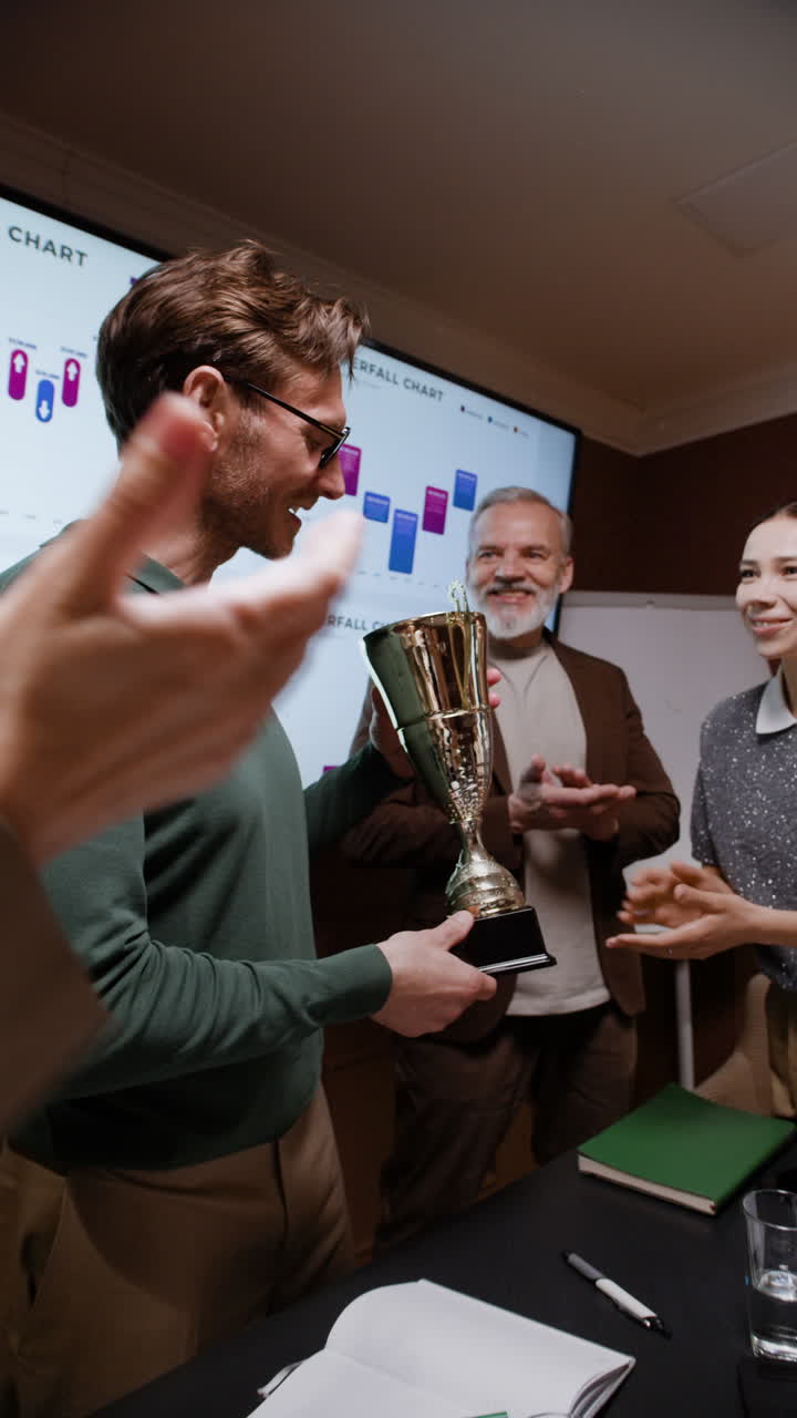 Man receives a trophy in a business meeting, celebrated by colleagues