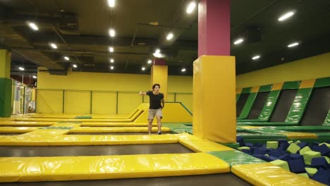 joven atleta esportivo excelentemente entrenado sobre secciones de trampolín realizando giros corporales.