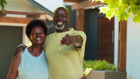portrait of senior couple outdoors holding keys to dream home