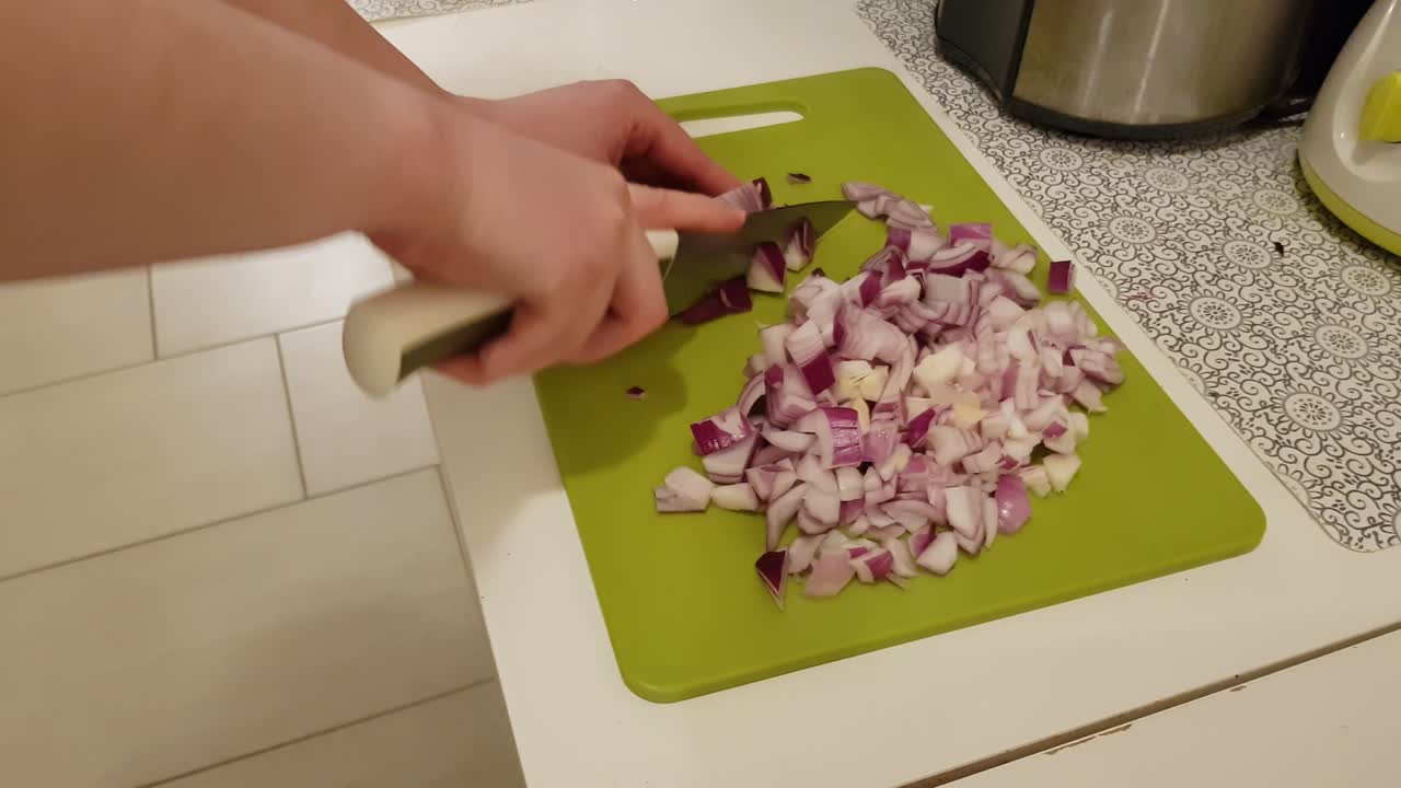 Caucasian woman cooking and cutting up purple onion