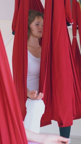 concentrated women sit and relax in butterfly anti-gravity yoga asana in special hammocks close view