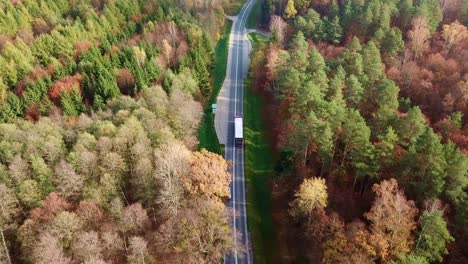 Vista-Aérea-De-Un-Camión-Que-Viaja-Por-Carretera-En-Un-Colorido-Bosque-De-Otoño