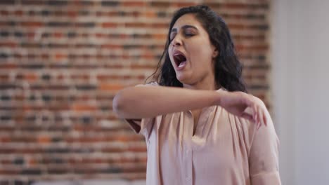 woman sneezing on her elbow at office